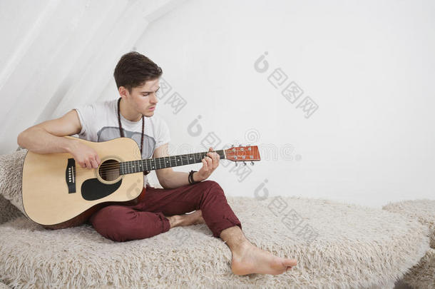 坐在毛皮沙发上弹吉他的年轻人