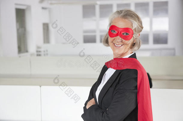 办公室里身着超级英雄服装微笑的资深女商人画像
