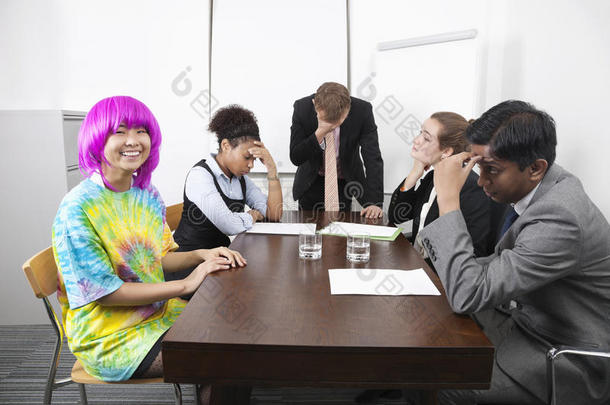 疲惫不堪的多民族商人和戴着粉色假发的同事开会