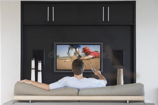 后视图的中年男子更换频道与电视遥控器在客厅
