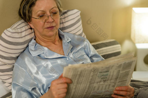 退休妇女睡前看报纸