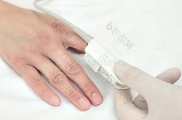 戴手套的医生把传感器放在病人的手指上。象征