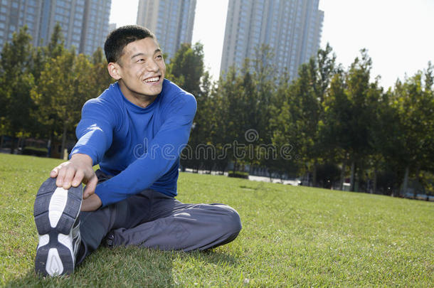 在北京公园伸展的年轻微笑运动员-水平