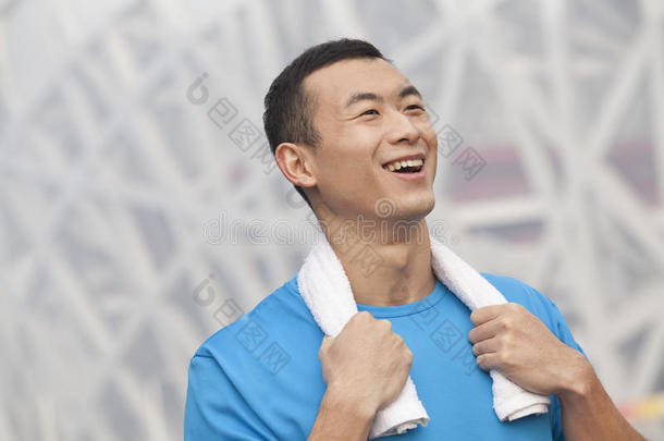 户外穿着蓝色t恤、脖子上围着毛巾的微笑着的年轻运动员的肖像