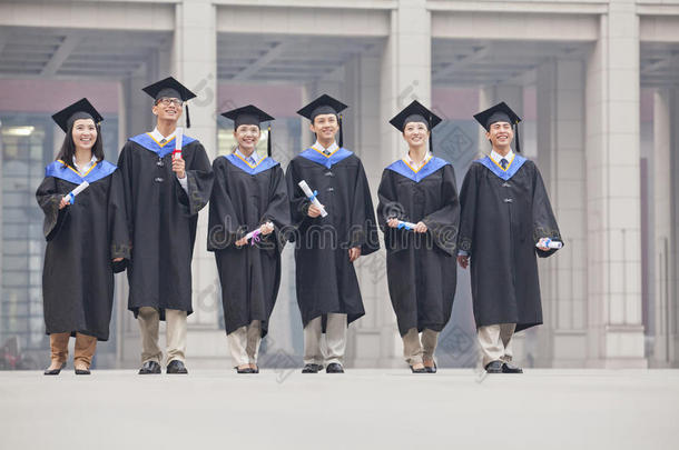 一群微笑的研究生身着毕业礼服，手拿毕业证书