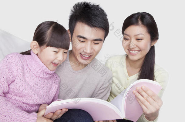 一家人聚在一起，微笑着在沙发上看书，低头看书，拍摄