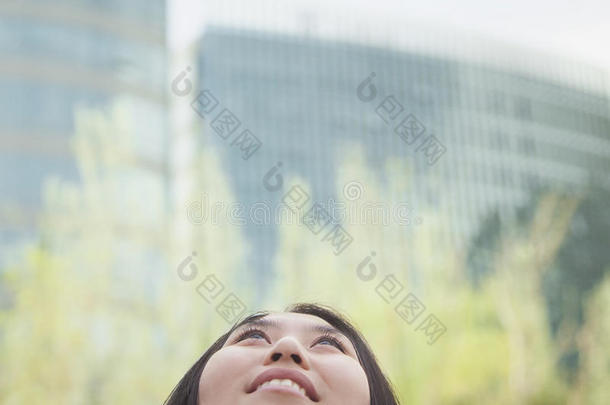 年轻女子抬头，背景是玻璃建筑