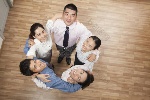 五个面带微笑的同事围成一圈，互<strong>相拥</strong>抱，抬头看着摄像机，俯拍