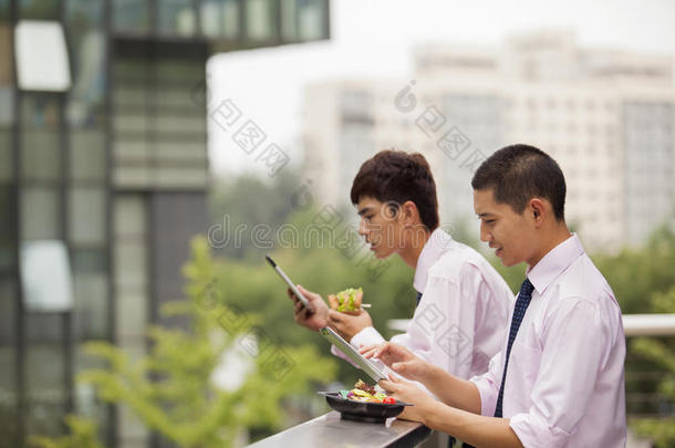 两个<strong>年</strong>轻的商人在午休时间在户外工作和吃饭