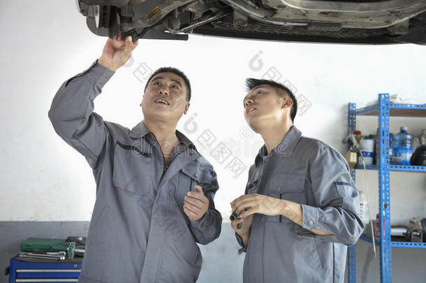 两个机械师看着<strong>汽车</strong>下面，讨论
