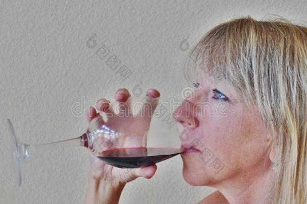 一个金发女人喝<strong>一杯</strong>或<strong>一杯红酒</strong>。
