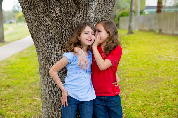 在公园树上玩耍的女孩们低声耳语