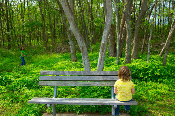 <strong>孤独的孩子</strong>坐在长凳上悲伤地看着森林