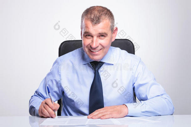 老商人在办公桌上签合同