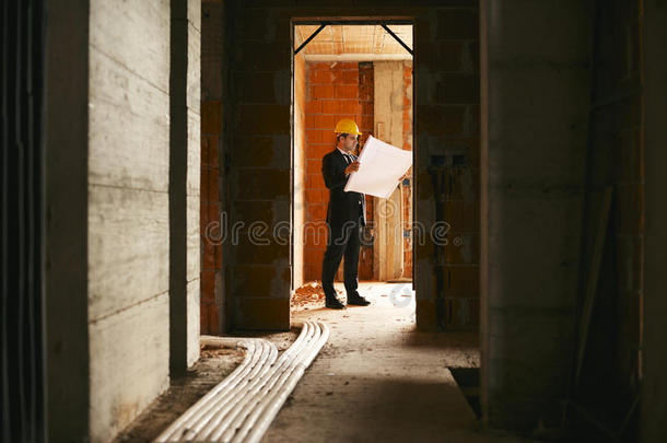 建筑师站在正在施工的房子里，有建筑平面图