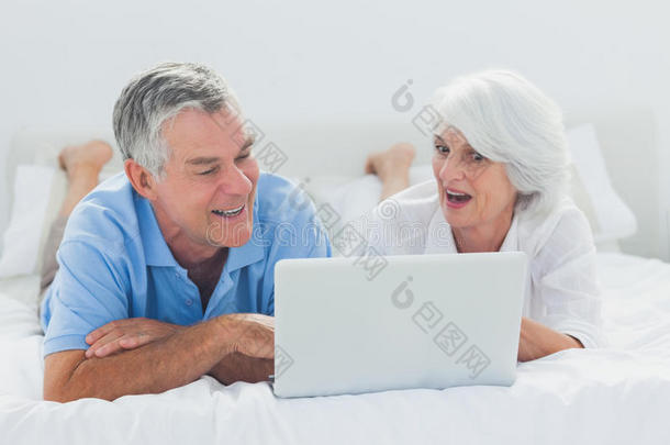 夫妻俩在床上用笔记本电脑