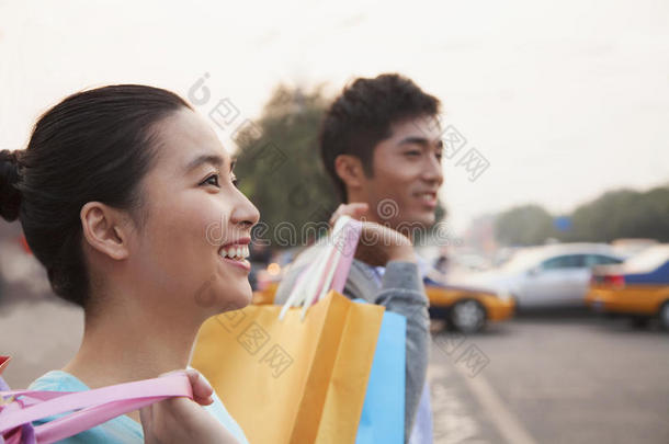 一对年轻夫妇提着购物袋在街上走来走去，特写