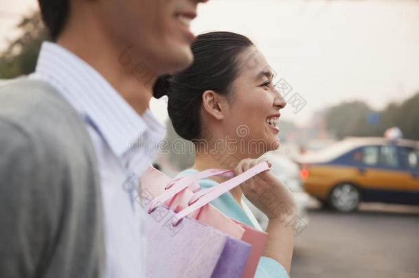 一对年轻夫妇提着购物袋在街上走来走去，特写