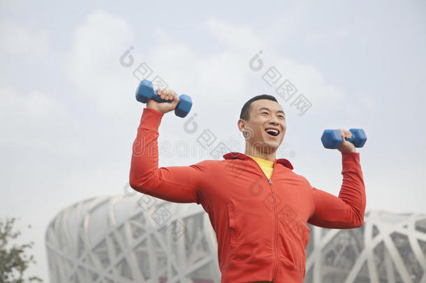 北京公园里一个拿着哑铃锻炼的年轻人
