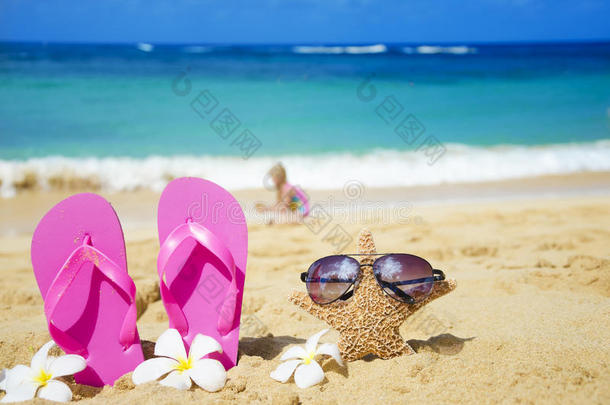 沙滩上带墨镜的人字拖和海星