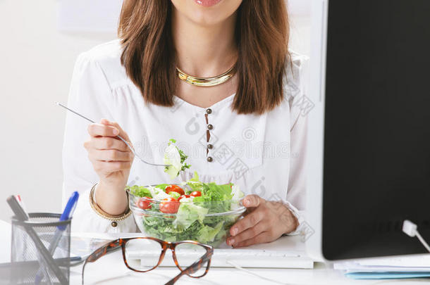 年轻的女创意设计师在办公室吃沙拉。