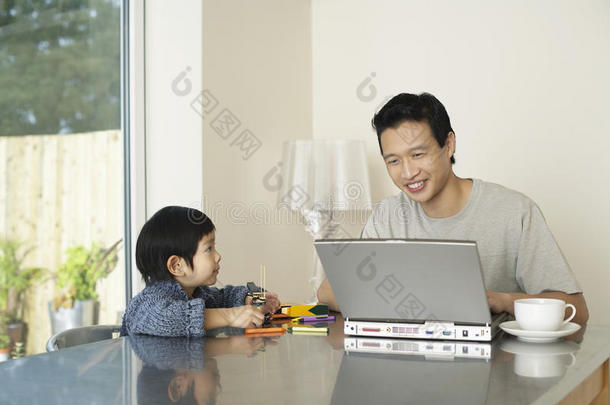父子俩带着笔记本电脑和颜色在桌子上