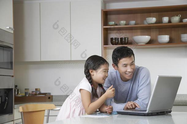 <strong>爸爸</strong>和女儿在<strong>厨房</strong>里拿着笔记本电脑
