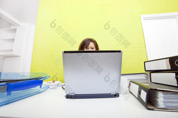 在办公桌上用笔记本电脑工作的白人年轻女子