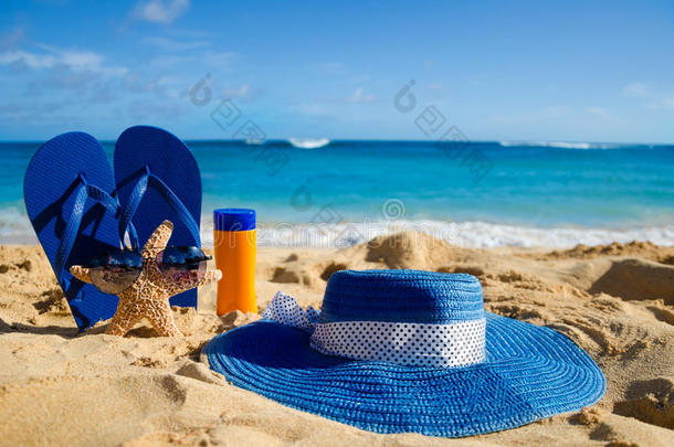 沙滩上的人字拖、防晒霜、帽子和海星