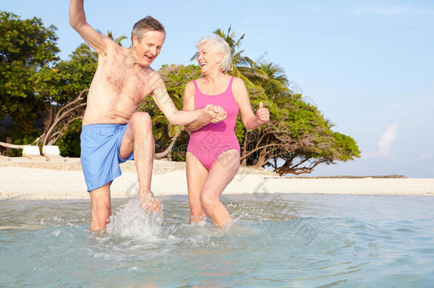 热带海滩度假中的老年夫妇在海上嬉戏