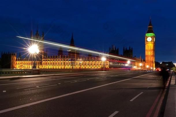 大本钟，伦敦和英国最突出的象征之一，与夜晚经过的汽车灯光一起展示