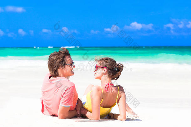 阳光明媚的夏日阳光下躺在沙滩上的年轻夫妇