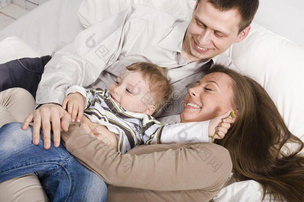 幸福家庭的画像，爸爸妈妈和儿子在床上玩耍