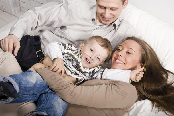 幸福家庭的画像，爸爸妈妈和儿子在床上玩耍