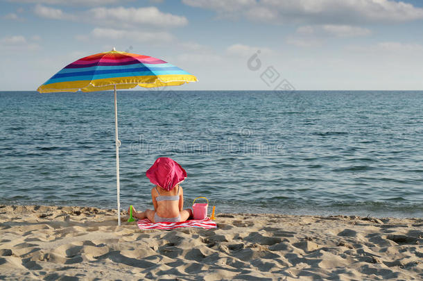 坐在沙滩<strong>遮阳伞</strong>下的小女孩