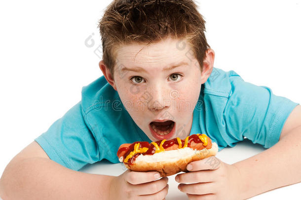 饥饿的小男孩在吃热狗。