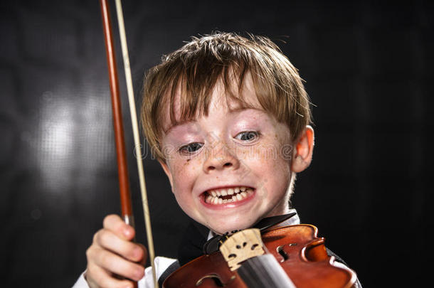 有雀斑的红头发男孩拉小提琴。