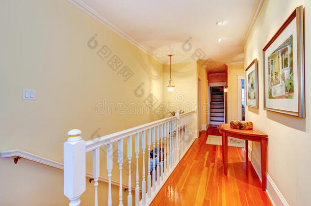 走廊有硬木地板和白色栏杆通往楼梯。