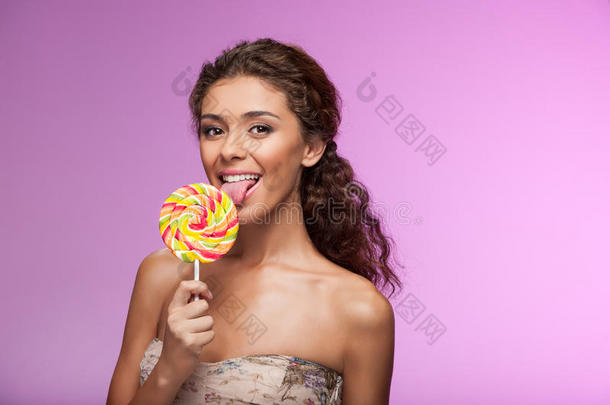 吃棒棒糖。 美丽的年轻女人一边吃棒棒糖，一边吃棒棒糖