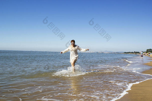 中年妇女靠海边的水跑步