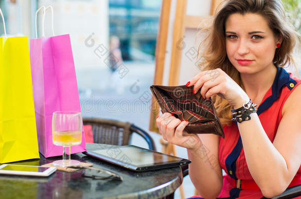 年轻漂亮的女人拿着空钱包。她正坐在咖啡馆里。