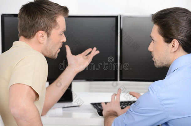 产生新的想法。 两个年轻的商人<strong>坐在电脑</strong>显示器<strong>前</strong>谈论生意