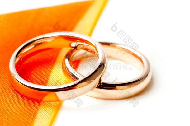 橙色丝带附近的金色结婚戒指