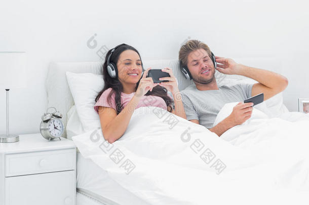 夫妻俩在<strong>床</strong>上用智能手机听音乐
