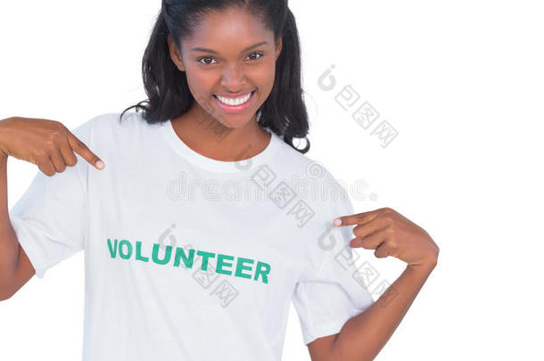 微笑的年轻女子，穿着志愿者T恤，指着它