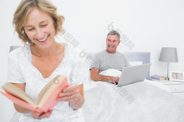当丈夫使用笔记本电脑时，女人正在看书