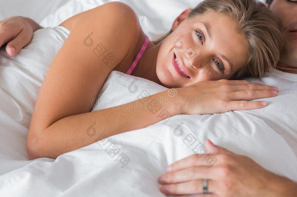 微笑的女人躺在丈夫的胸前躺在床上