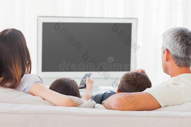 一家人坐在沙发上一起看电视