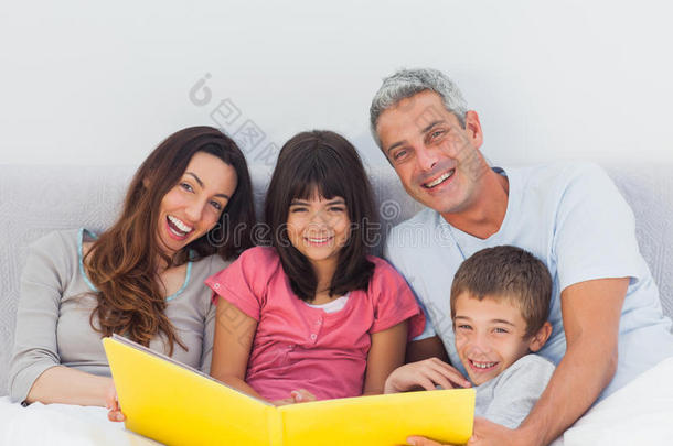 微笑的一家人在床上一起看相册