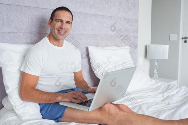 快乐男人在床上用笔记本电脑